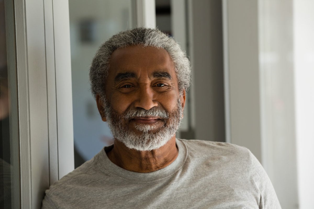 Portrait,of,senior,man,standing,at,the,entrance,of,house